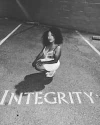 a woman kneeling in a parking lot with the word integrity written on it